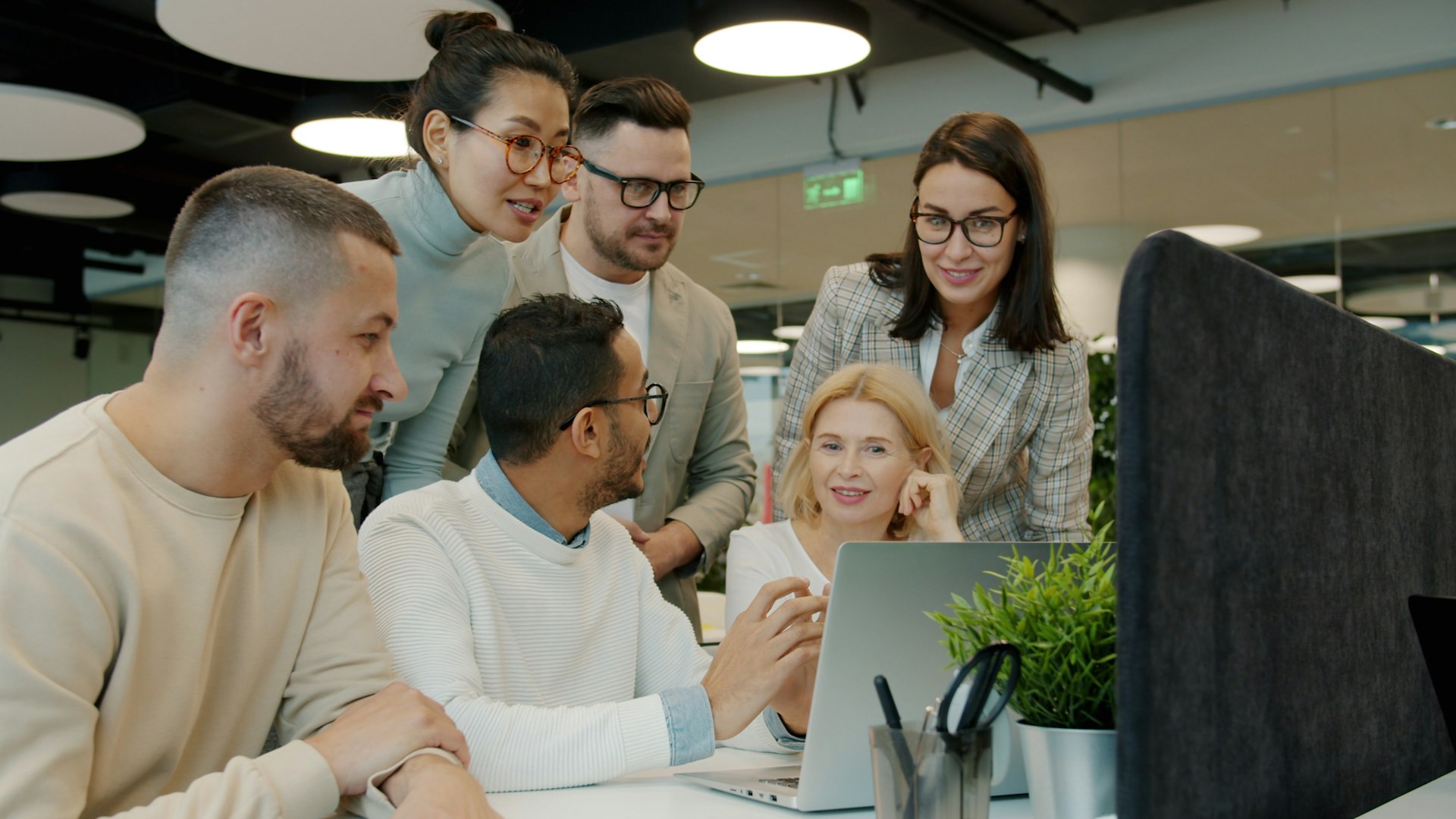 Team collaborating around a laptop in a modern office